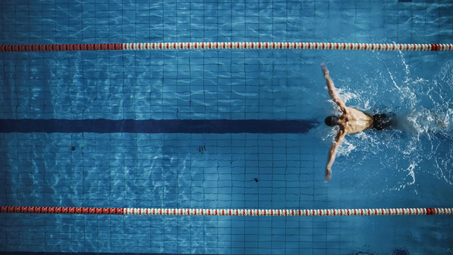 Luftaufnahme eines männlichen Schwimmers, der im Schwimmbad schwimmt.